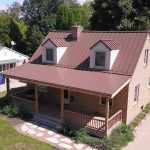 Tan house with Red Standing Seam Metal Roof